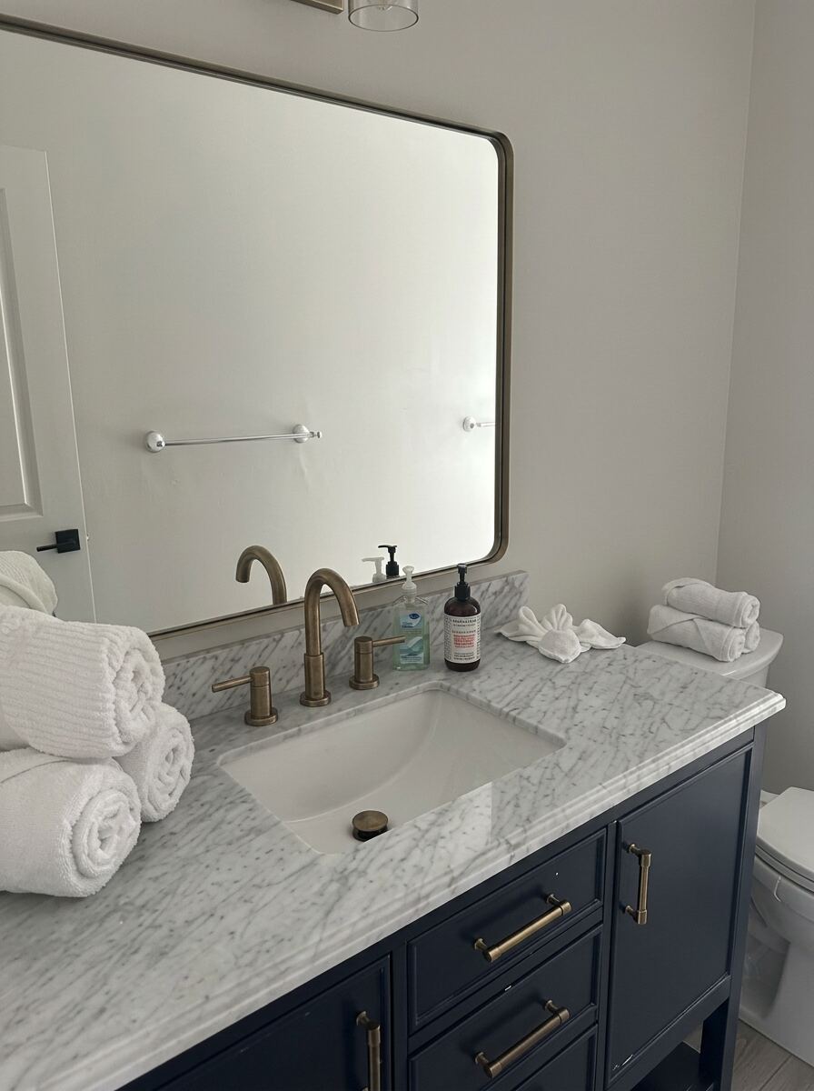 Airbnb bathroom vanity with rolled towels, polished mirror and spotless marble counter