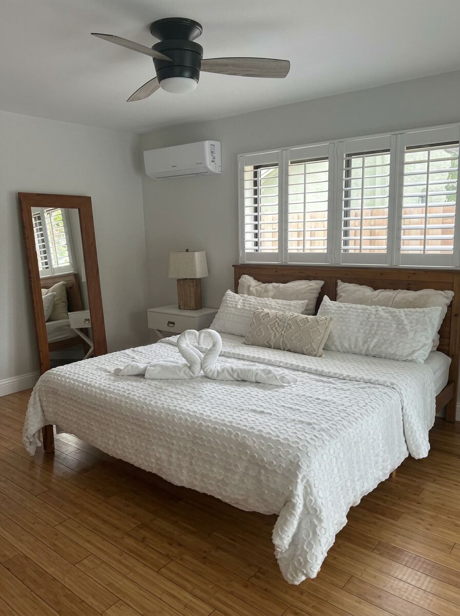 Airbnb bedroom staged with fresh linens and decorative towel swan on the bed