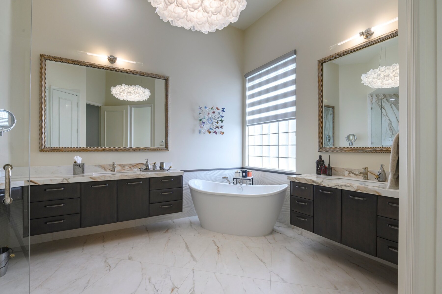 Spacious primary bathroom with marble floors, freestanding soaking tub and dual vanities, professionally cleaned