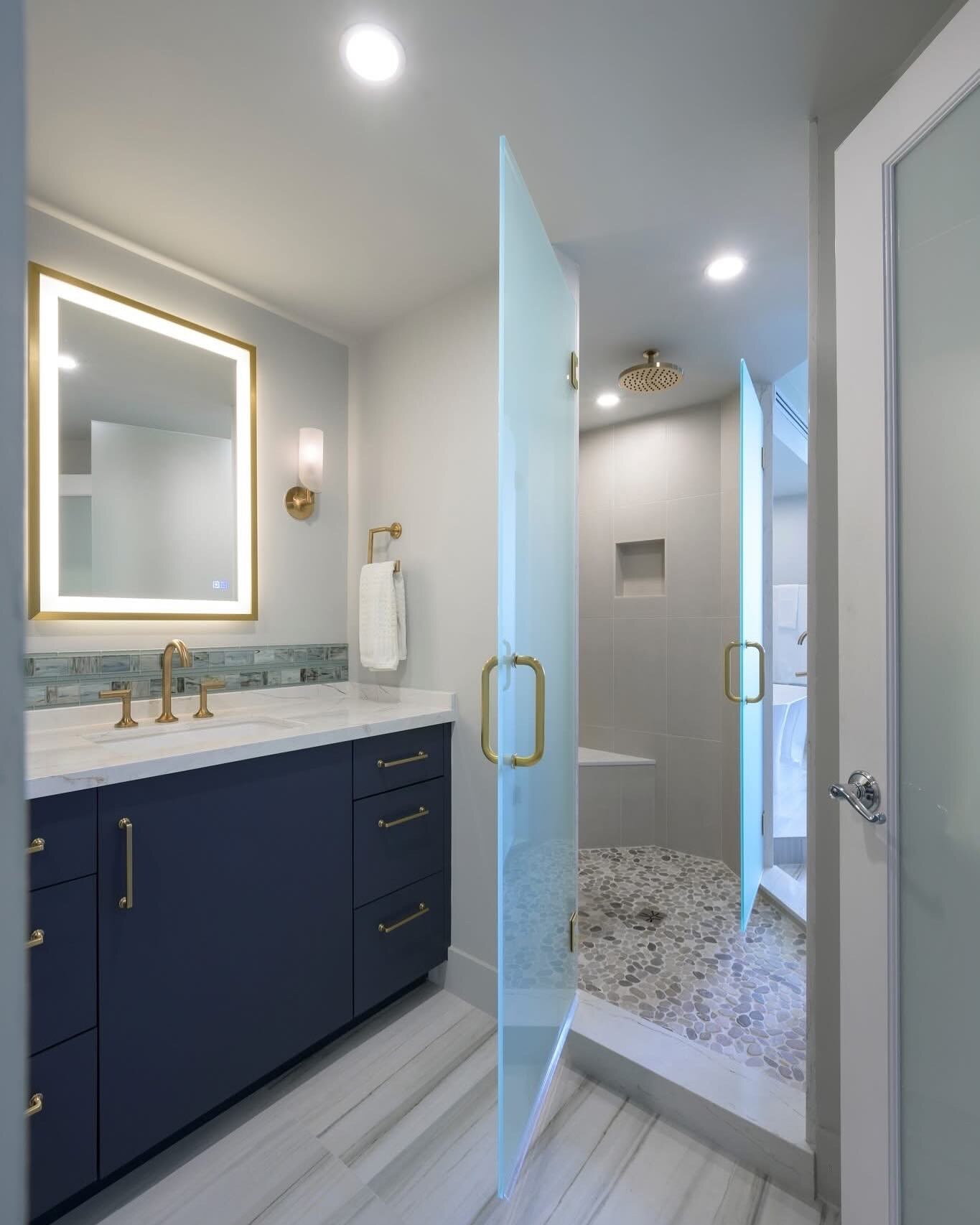 Modern St. Louis bathroom with navy vanity, brass fixtures and walk-in glass shower after cleaning