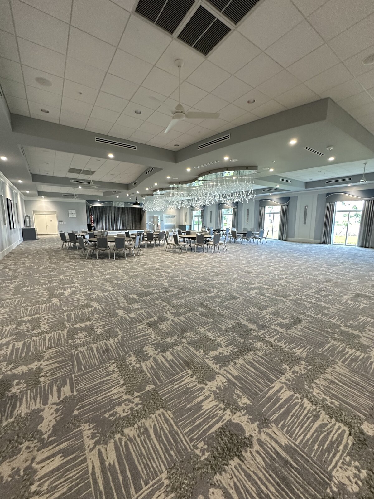 Spotless event ballroom with vacuumed patterned carpet, chandelier and banquet seating