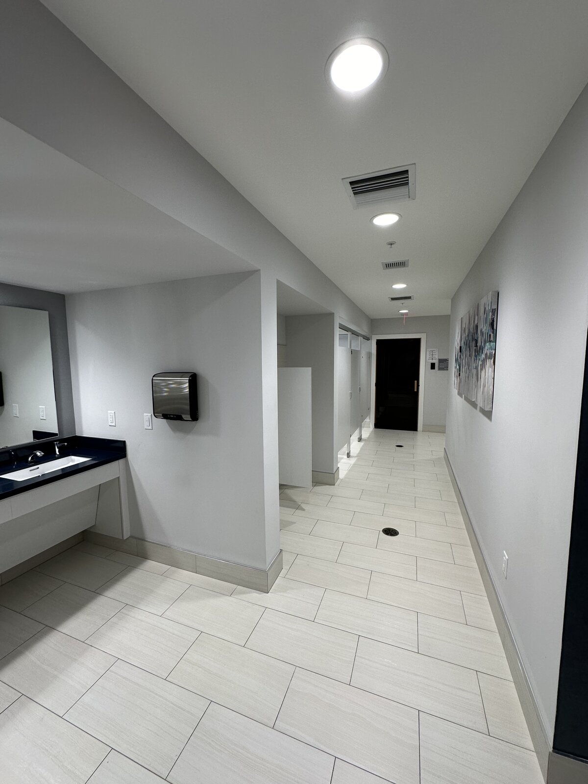 Commercial restroom with sanitized fixtures, polished tile and stocked dispensers