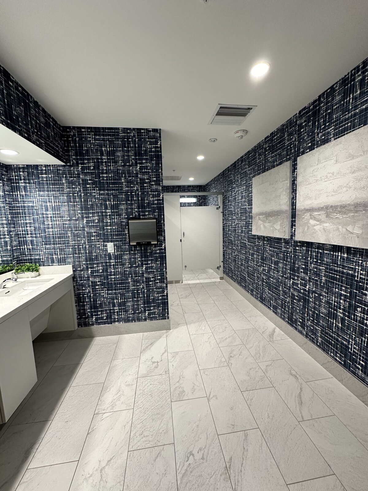 Designer office restroom with detailed tile, polished mirror and clean vanity