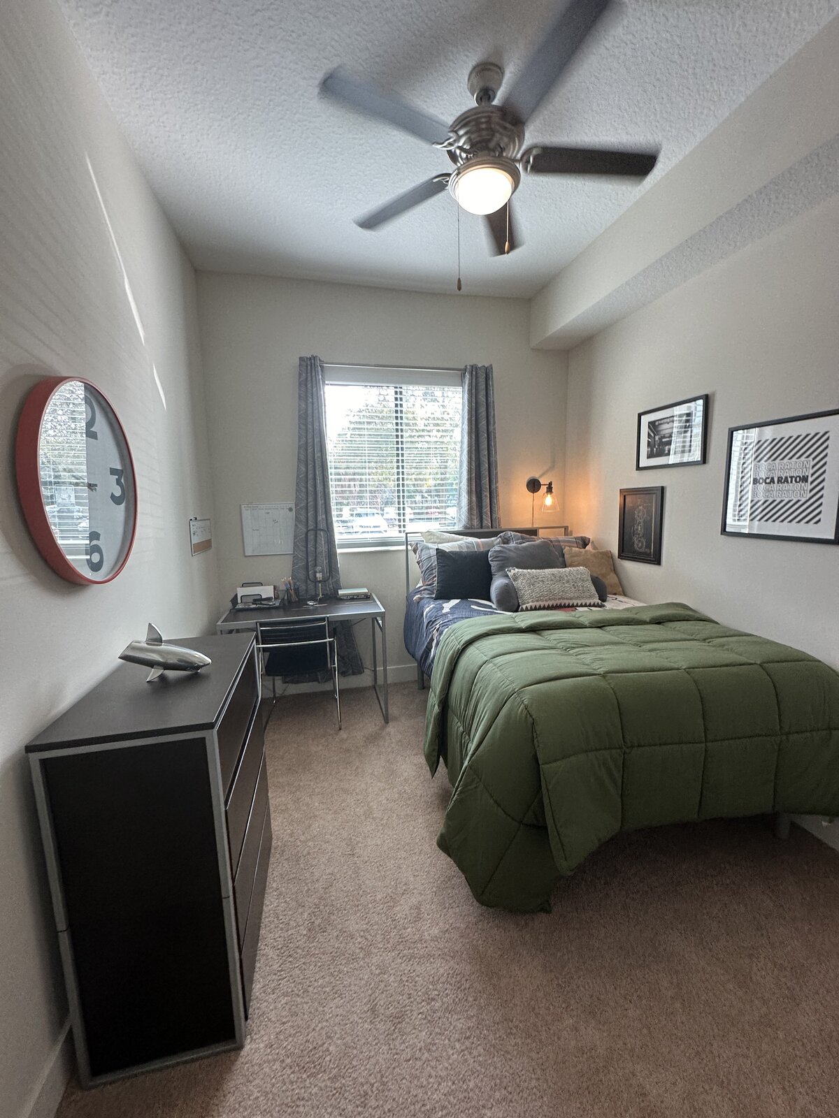 Dorm bedroom with green comforter, vacuumed carpet and dust-free surfaces